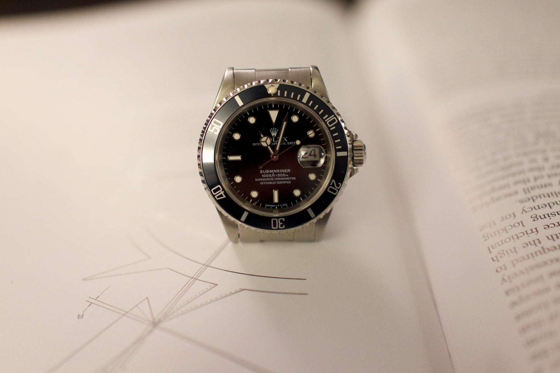 Luxury stainless steel dive watch with black bezel and dial displayed on an open book
