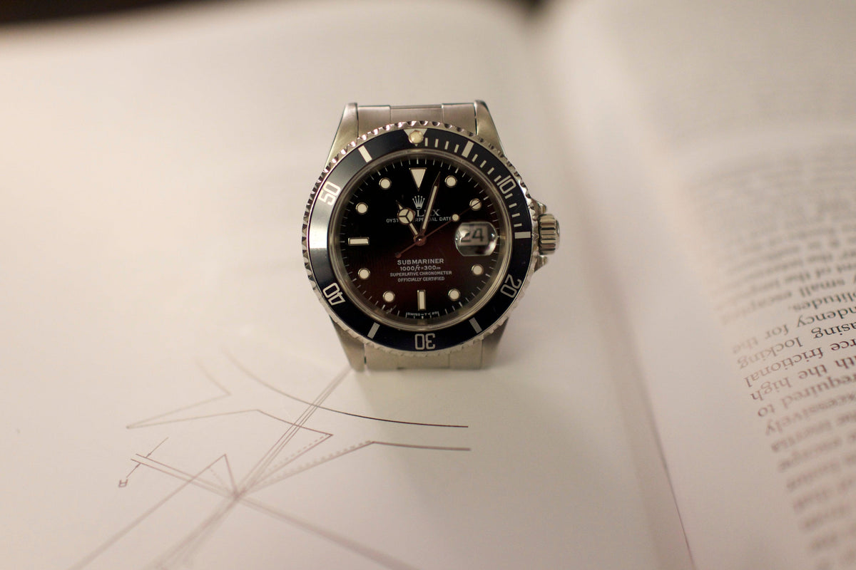Luxury stainless steel dive watch with black bezel and dial displayed on an open book