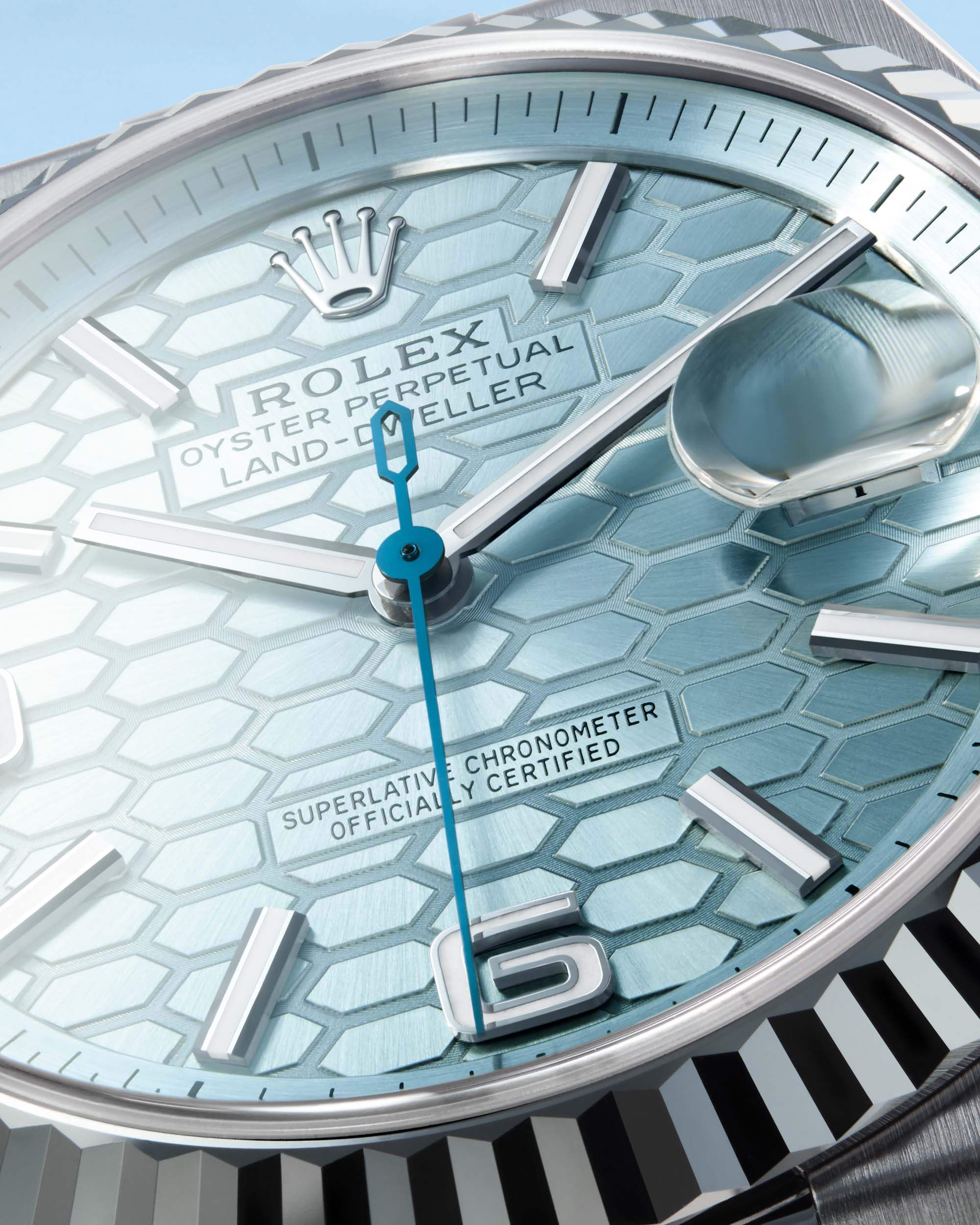 Close-up of luxury Swiss watch with blue honeycomb dial, silver markers, and date magnifier.