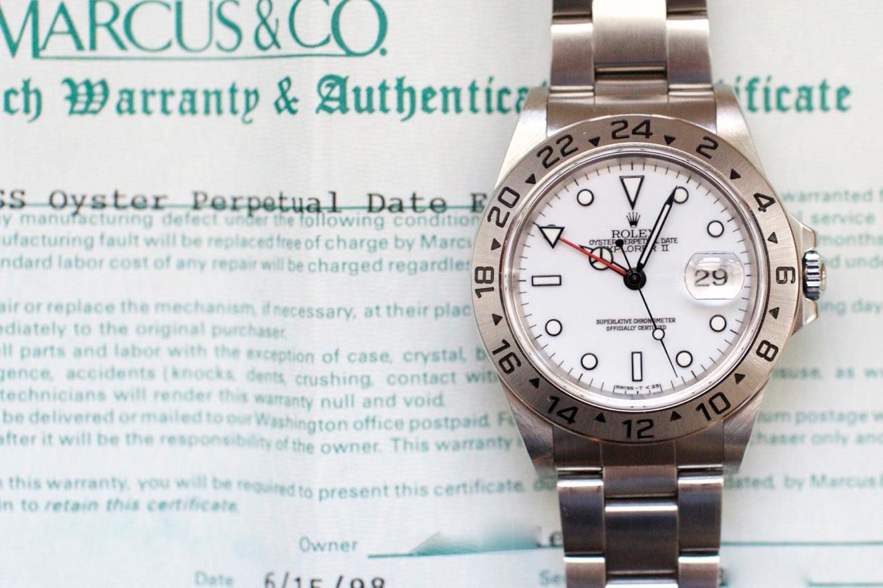 Stainless steel luxury watch with white dial and date, placed on an authenticity certificate