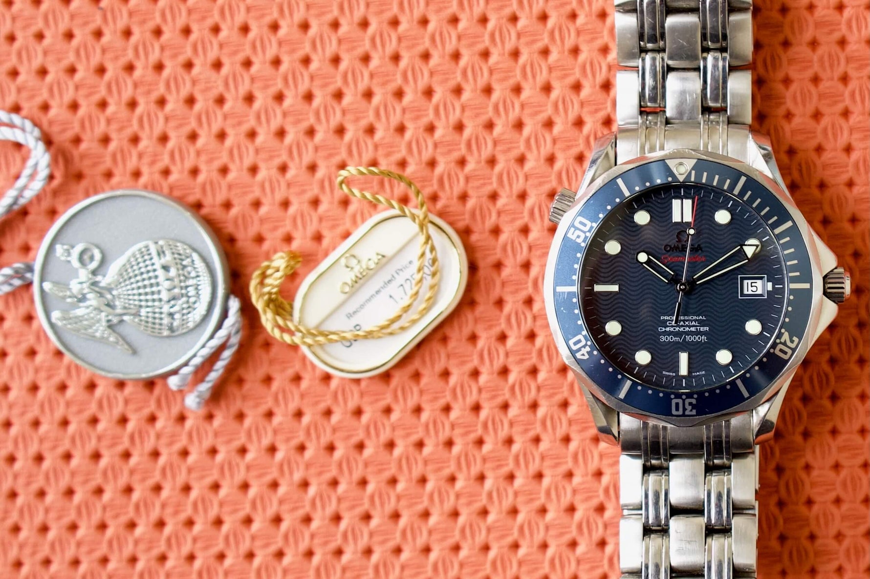 Omega Seamaster Professional blue dial luxury dive watch with tags on textured orange background