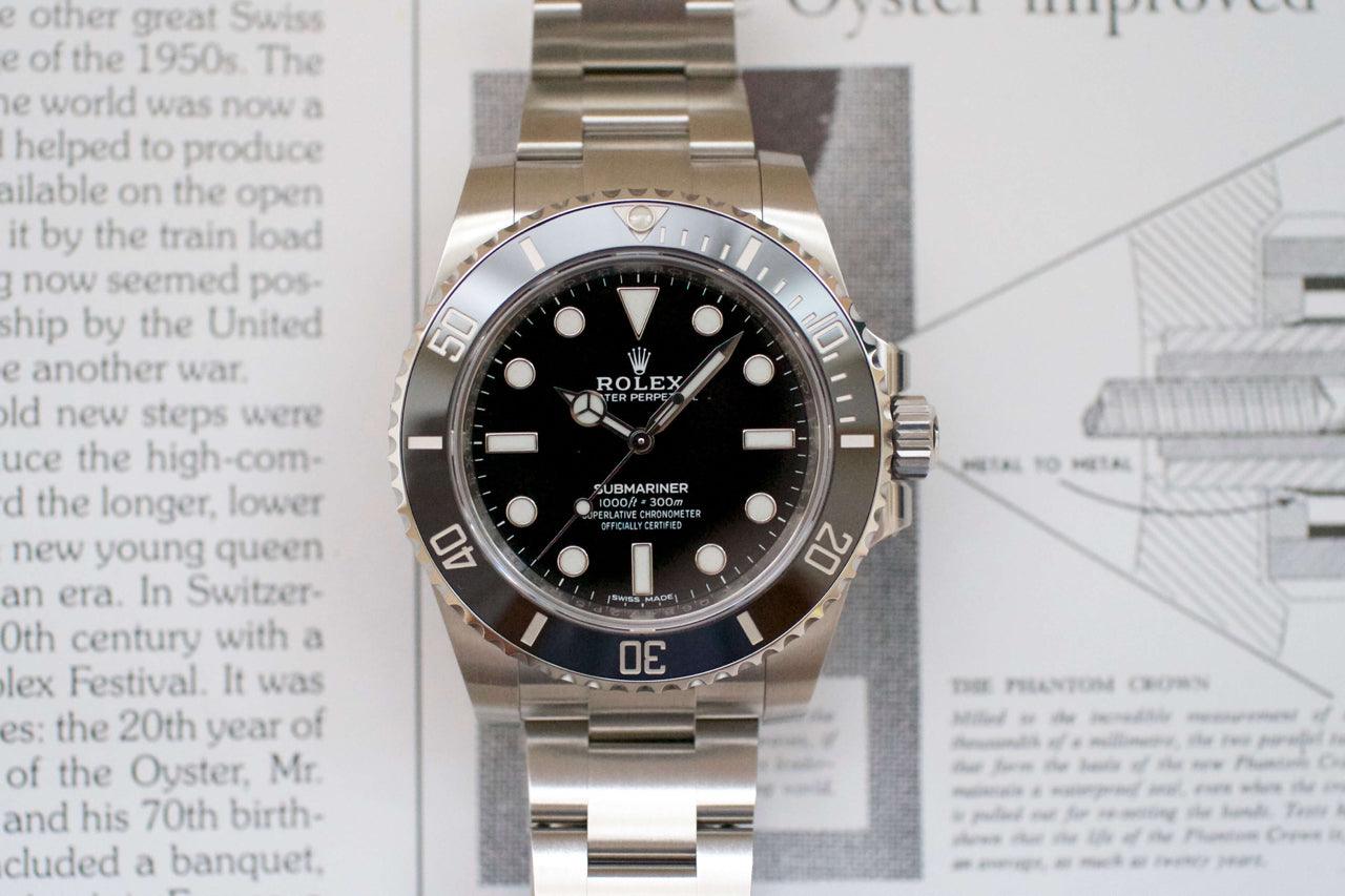 Stainless steel luxury dive watch with black dial and rotating bezel, close-up on book background