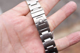 Close-up of a stainless steel Rolex watch bracelet clasp on a person's hand.