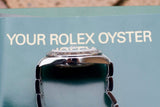 Close-up of a luxury Rolex Oyster watch resting on its original green owner's manual.