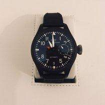 Black luxury pilot watch with black strap displayed on white holder, pre-owned timepiece