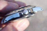Close-up side profile of a luxury Swiss watch showing the crown and bezel.