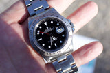 Close-up of a Rolex Explorer II luxury watch with a black dial and steel bracelet.