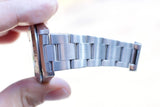Close-up of a silver stainless steel luxury watch bracelet held by a person.