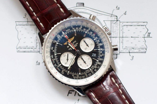 Luxury men's chronograph watch with black dial, silver case, and brown leather strap on sketch