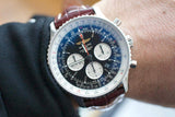 Men's chronograph watch with black dial, three subdials, and brown leather strap on wrist