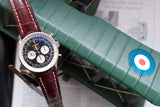 Men's chronograph watch with black dial and brown leather strap on green object
