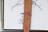 Tan leather watch strap with visible wear, placed on technical watch sketch background.