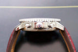 Side view of a luxury stainless steel chronograph watch with pushers and leather strap