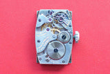 Close-up of a vintage Gruen Guild Swiss-made watch movement on a red background