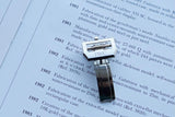 Close-up of an IWC luxury watch component resting on a document describing watch history.