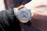 Close-up of a vintage Jaeger-LeCoultre automatic watch with a brown leather strap on a wrist