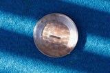 Close-up of a silver luxury watch case back with engravings on a blue textured surface