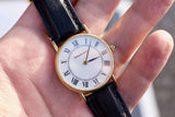 Close-up of a Tiffany & Co. luxury watch with Roman numerals and a black leather strap.