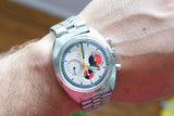 Close-up of an Omega Seamaster chronograph luxury watch with a silver steel bracelet on a wrist.