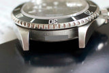 Close-up of stainless steel Swiss luxury dive watch with black unidirectional bezel.