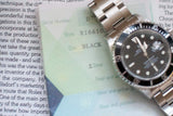 Stainless steel black dial watch with paperwork, model R16610, close-up view