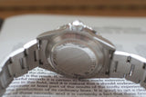 Close-up of stainless steel luxury watch case back and bracelet on an open book