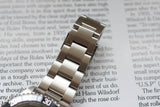 Stainless steel luxury watch bracelet and bezel macro on a book background