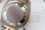 Close-up of stainless steel and gold luxury Swiss watch caseback on a document background