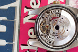 Close-up of luxury watch movement with open caseback showing intricate gears and rotor