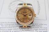 Luxury two-tone Datejust watch with champagne dial and fluted bezel on a book page