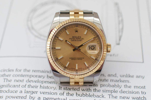 Luxury two-tone Datejust watch with champagne dial and fluted bezel on a book page