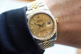 Gold and silver luxury watch with champagne dial and date display on wrist