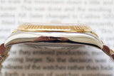 Close-up side view of luxury two-tone watch case with gold fluted bezel on blurred text