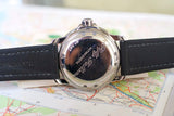 Close-up of Blancpain Fifty Fathoms watch caseback with black leather strap on a map
