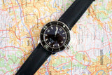 Luxury Blancpain Fifty Fathoms dive watch with black strap placed on a colorful map