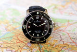 Blancpain Fifty Fathoms luxury dive watch with black dial on a map background