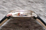 Close-up profile view of a luxury Swiss watch with stainless steel case and black leather strap