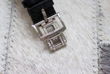 Close-up of a luxury watch stainless steel deployment clasp with a black leather strap