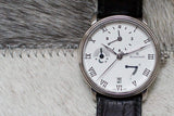 Silver case luxury Swiss watch with moonphase, subdials, and black leather strap on fur background