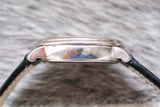 Side profile of a silver luxury watch case with black leather strap