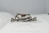 Side view of a stainless steel luxury watch with metal bracelet resting on an open book
