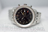 Stainless steel chronograph luxury watch with black dial and metal bracelet on open book