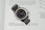 Stainless steel chronograph watch with black dial and metal bracelet resting on an open book