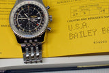 Stainless steel chronograph watch with black dial on a yellow warranty booklet