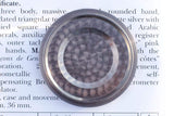 Close-up of the silver-toned case back of a Swiss-made luxury watch on a document.