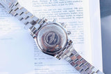 Back view of a luxury Breitling chronograph watch with a silver bracelet on a document.