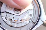 Close-up of a watchmaker's hand working on a luxury Swiss watch movement.