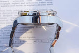 Side view of a luxury silver Swiss watch resting on an official certification document.