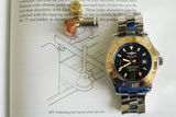Breitling Superocean 44mm luxury Swiss watch with steel bracelet on an open book, near bullets