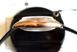 Side view of vintage 14k rose gold watch case with domed crystal and black leather strap